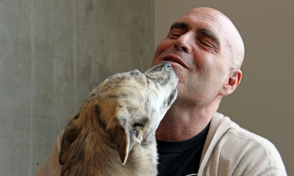 Man getting licked on the face from a happy dog