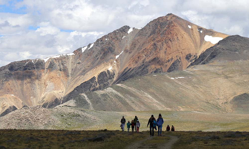 A group of people walking on the foreground, as the Sierra Nevadas loom in the distance