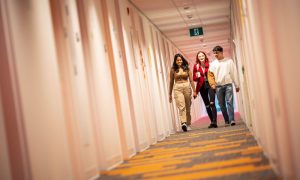 Three students walking down a residence hallway.