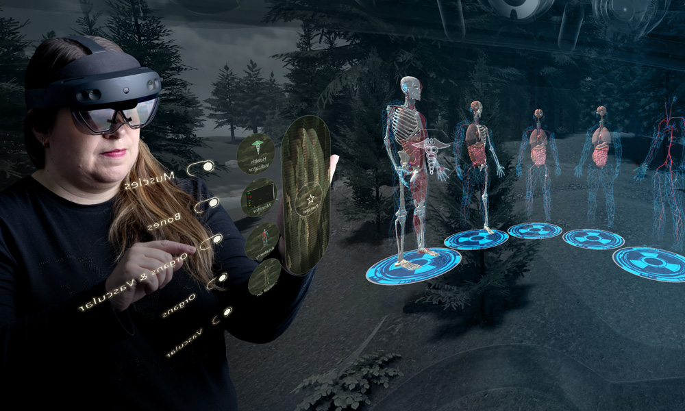 Carla Mather is pictured against a black background with a Microsoft HoloLens on her head. Her hands are up like she is reading a book, with one finger pointing to something in the air. An image of skeletons with vascular details in hovering as a hologram behind her