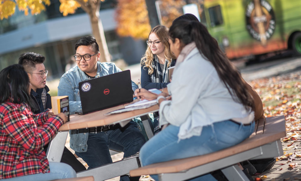 Students sitting at a picnic table in the courtyard.