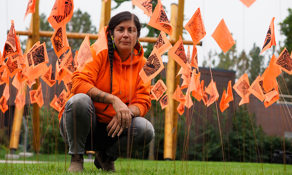 Tania Willard sits amongst hundreds of small orange flags.