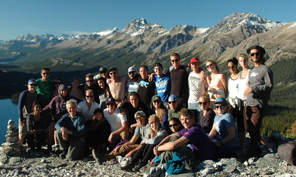 A group of individuals posing in front of a mountain landscape.