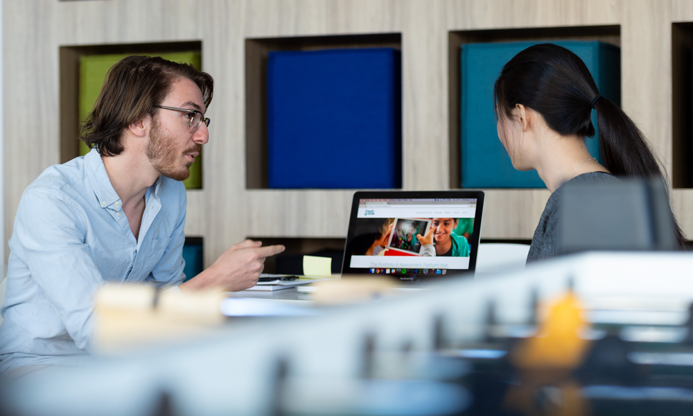 A tech employee mentoring a co-op student over a laptop.