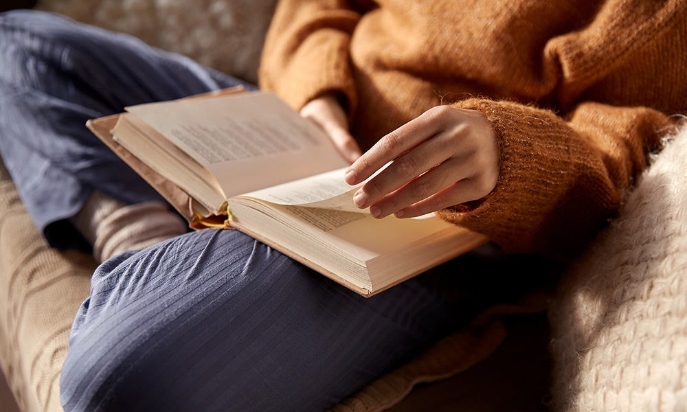 A woman sitting on the couch reading.