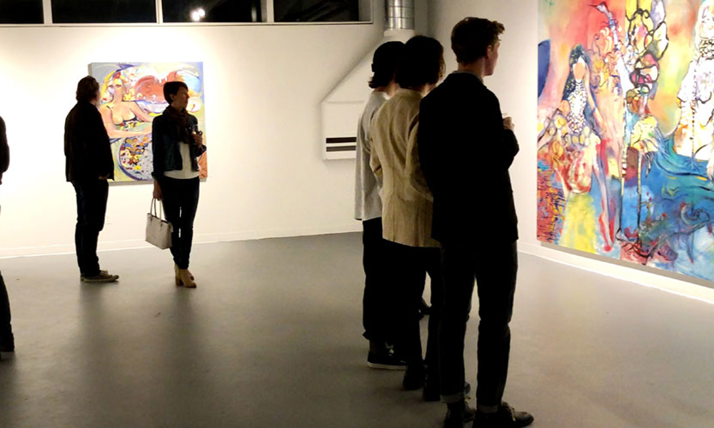 Attendees viewing art in a gallery exhibition.